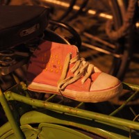 Lost sole. Tiny girls 'Chuck Taylor' abandoned and placed on the luggage rack of a green bicycle.