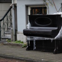 Abandoned street piano getting warped in the rain.