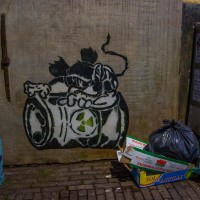 Toxic Mickey random street art behind some trash in an alley.