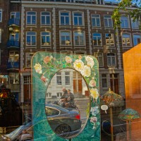 Reflections of reflections. Mirror catching cyclists while the window reflects the buildings
